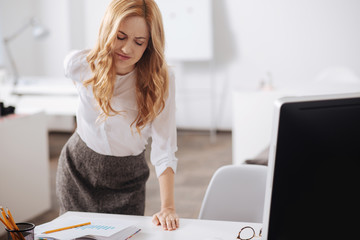 Distracted young woman feeling pain in her back in the office