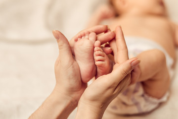 Mother holding tiny foot of newborn baby - obrazy, fototapety, plakaty