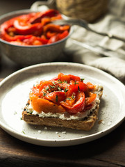 Vegetarian toast with baked pepper and cream cheese on a plate on a wooden board
