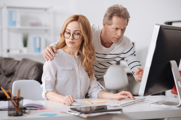 Mature office manager hugging young colleague in the office