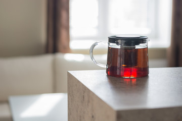 Transparent teapot on the white table. Natural light from the window.