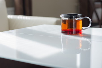 Transparent teapot on the white table. Natural light from the window.