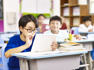 Fototapeta na wymiar asian primary school student using tablet in classroom