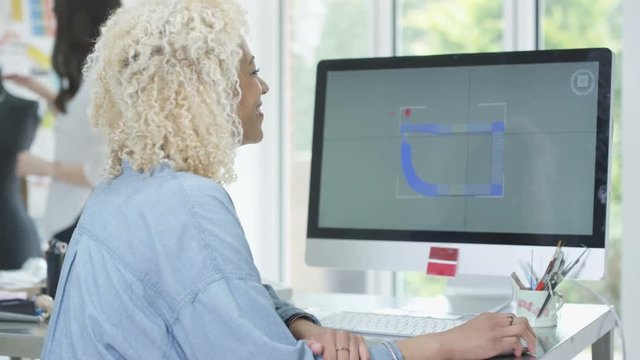  Jewelry designer at her desk working on computer with 3D modeling software. 