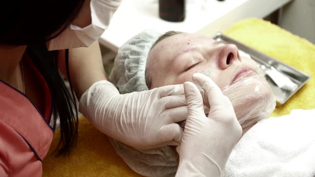 Beautician making injections to the cheek for the woman