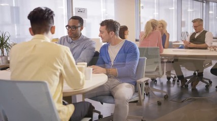  Happy professional group drinking coffee & chatting in office breakout area
