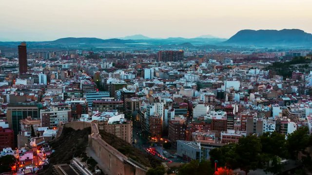 Costa Blanca, Spain. Aerial view of Alicante, Spain in the evening. It is a popular summer resort of Costa Blanca. Time-lapse, illumination at sunset. Mountains at the background