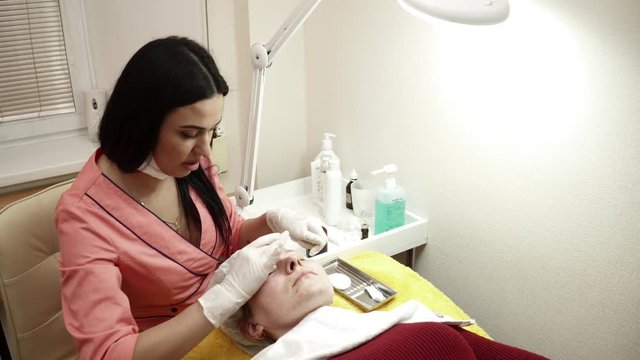 Beautician covering woman's face with gel after the anti aging procedure
