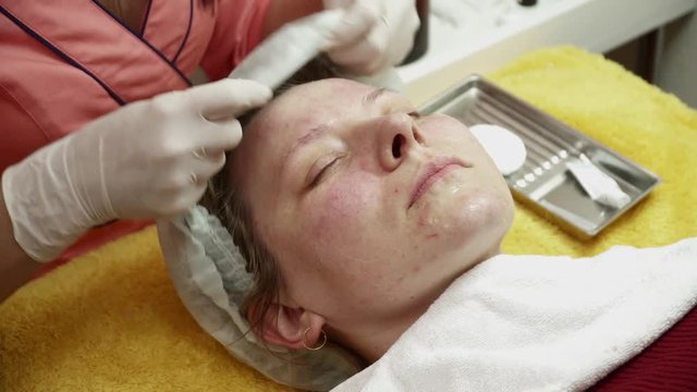 Beautician covering woman's face with gel after the anti aging procedure closeup