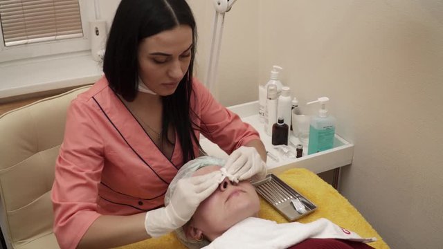 Beautician covering woman's face with gel after the anti aging procedure in salon