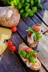 Healthy brown bread with ham, cheese and tomatoes on a wooden table.