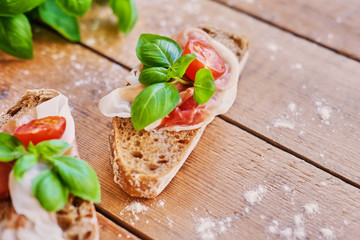 Healthy brown bread with ham, cheese and tomatoes on a wooden table.