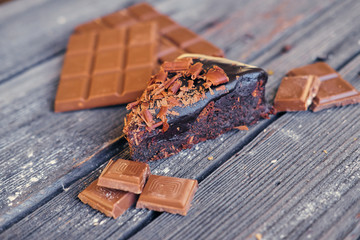 Pieces of a dark chocolate on a grey wooden table.