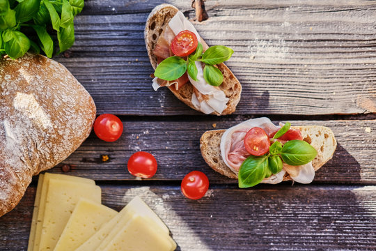Healthy brown bread with ham, cheese and tomatoes on a wooden table.