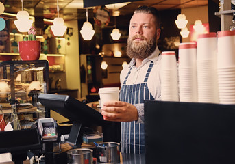A man at the counter using cash register in a coffee shop.