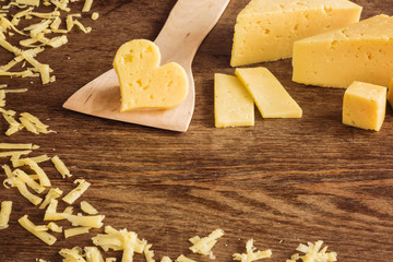 Cheese peaces on the old wooden table in the kitchen. Dairy product. Healthy eating and lifestyle.
