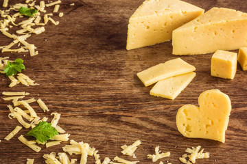 Cheese peaces on the old wooden table in the kitchen. Dairy product. Healthy eating and lifestyle.