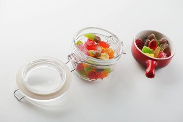 Ceramic and crest containers with candies on white background.