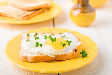 Toast with egg in yellow plate on white wooden background. Healthy breakfast