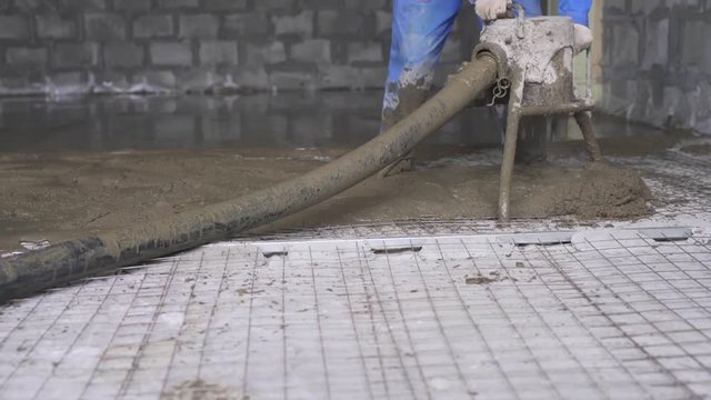 Worker making cement screed on the floor view