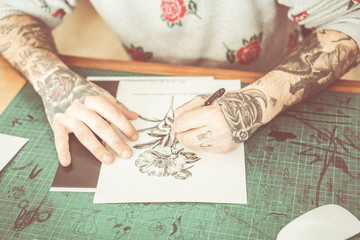Tattoo artist drawing new flower illustration inside ink studio