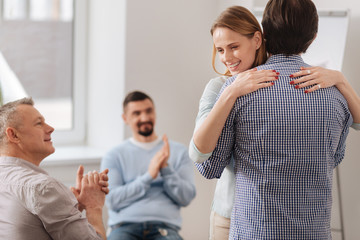 Positive young woman holding hands on male shoulders