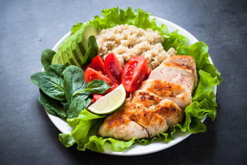 Fresh salad from quinoa, chicken breast, spinach, lettuce and tomatoes. Organic food. Healthy meal portion plate.