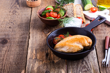 Fried chicken breast on skillet with tomato cucumber salad and yogurt sauce