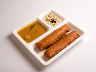 Banana bajji or Vazhakkai bhaji with sambar and coconut chutney served in a white plate 