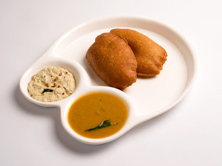 vengayam bhaji(onion fritter) with sambar and coconut chutney served in a plate on white background