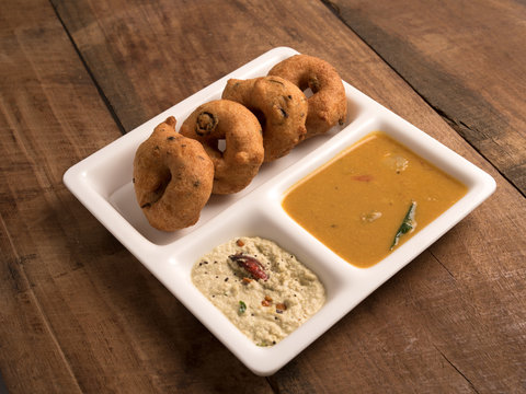 medhu vadai (Ulundu vadai) with sambar and chutney served in a white plate on wooden background