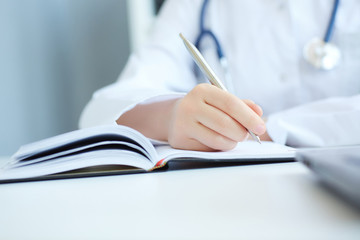 Close up of doctor's hands taking notes. Ward round, patient visit check, medical calculation and statistics concept. Physician ready to examine patient