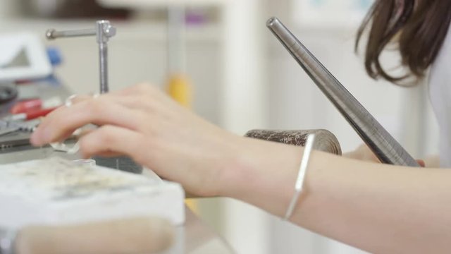  Jewelry designer working in studio using a tool to work on a ring. 