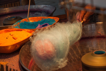 man making colored and flavored sugar cotton candy in a fair trade 