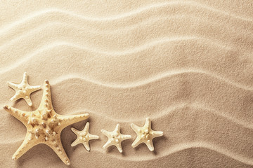 Fototapeta na wymiar Sea star fish on an idylic tropical beach with ripples in the sand. Tree starfish as concept for summer holiday or vacation, texture background with copy space...