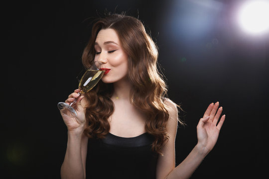 Smiling pretty young woman standing and drinking chamagne