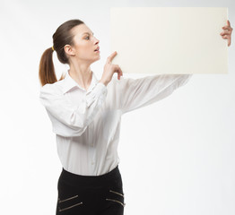 Young happy woman showing presentation, pointing on placard over gray background