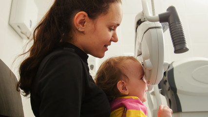 Children ophthalmology - mother and cute little girl - optometrist Checks Child's Eye