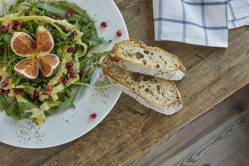 Fresh figs and pomegranate in arugula salad. Overhead, top view.