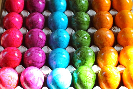 Full background of colorful bright rainbow painted easter eggs in sunlight. Selected focus.
