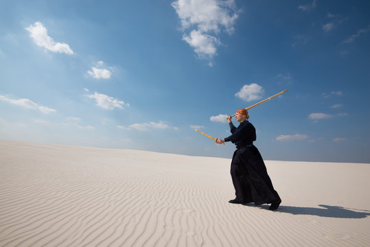 Concentrated man is practicing martial arts in a desert