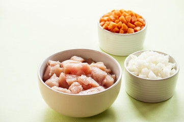 Raw chicken small pieces close up on wooden background with vegetables