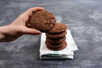 Picture of hands hold chocolate cookies over wooden background