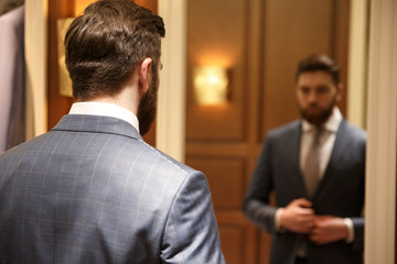 Fototapeta premium View from back of bearded man looking at the mirror