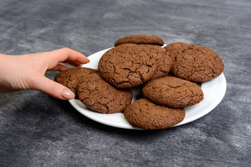 Picture of hands holding chocolate cookies over wooden background