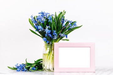 Bouquet of blue spring flowers and a pink frame mock up