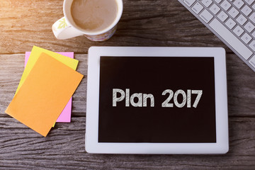 Tablet pc with Plan 2017 and a cup of coffee on wooden background.
