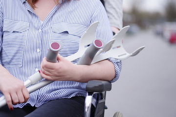Frau im Rollstuhl mit Krücken