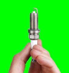 Mechanic holds a spare part spark plug in his hand. Auto part spark plug close-up on a green screen background.