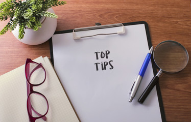 Tops Tips word on paper with glass ballpen and green plant.